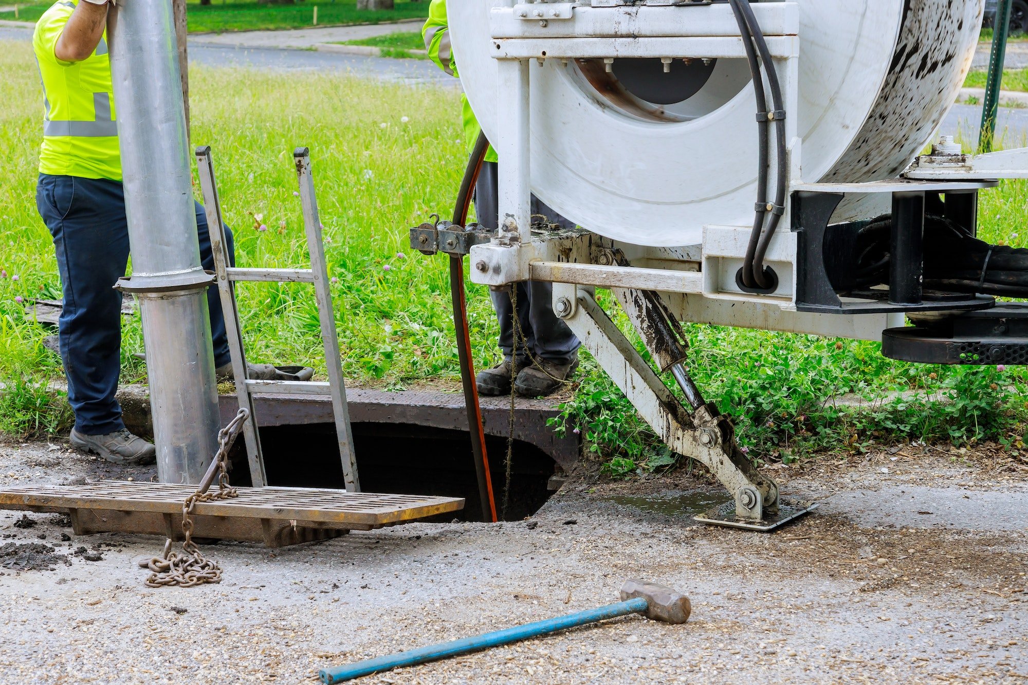 Professional using a high pressure jetting machine to unblock a pipe on the road.